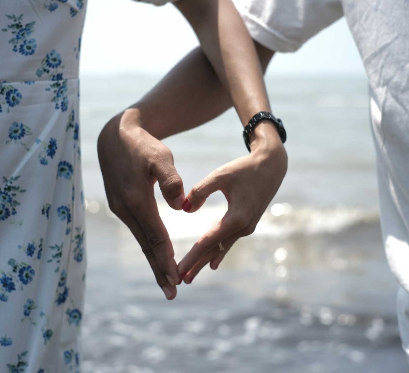 A couple making a heart with their hands at the beach